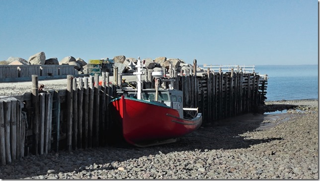 A red boat, and a then a blue boat, at low tide in Margaretsville